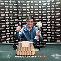 a man holding a poker trophy in front of a table